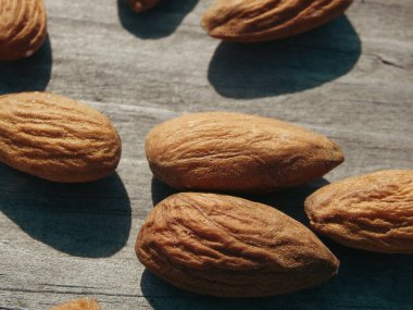 Gri ahşap masa arkasında badem fıstığı. Soyulmuş bademler ahşap bir masada..