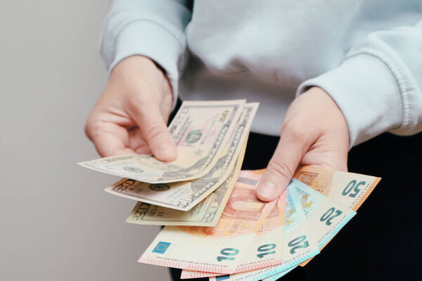 Exchange US dollar or American dollars (USD) for EUR money. Female hands holding American and European banknotes. Woman hands counting money American dollars and Euro. Planning budget, home economy.
