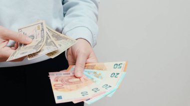 Amerikan Doları veya Amerikan Doları (USD) ile EUR parasını takas edin. Amerikan ve Avrupa banknotlarını tutan kadın eli. Kadın, Amerikan dolarlarını ve Euro 'yu sayıyor. Planlama bütçesi, ev ekonomisi.