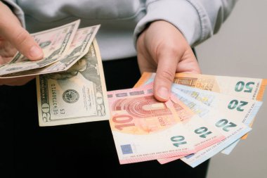 Amerikan Doları veya Amerikan Doları (USD) ile EUR parasını takas edin. Amerikan ve Avrupa banknotlarını tutan kadın eli. Kadın, Amerikan dolarlarını ve Euro 'yu sayıyor. Planlama bütçesi, ev ekonomisi.