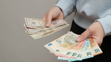 Amerikan Doları veya Amerikan Doları (USD) ile EUR parasını takas edin. Amerikan ve Avrupa banknotlarını tutan kadın eli. Kadın, Amerikan dolarlarını ve Euro 'yu sayıyor. Planlama bütçesi, ev ekonomisi.