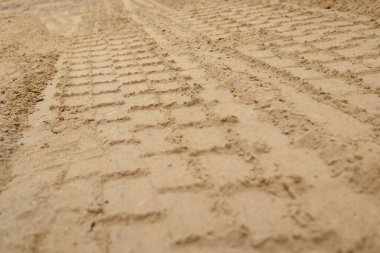 Tekerlek koruyucusu dokuyu belirler. Plaj kumlarında lastik izleri ve ayak izleri. Araba lastik izleri.