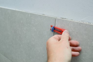 Tiler 'ın eli sistem kiremitlerini düzleştiriyor. Döşemeler için düzleştirme sistemi takozları. İşçi Yerleri Yeni Döşeme