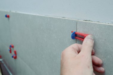 Tiler 'ın eli sistem kiremitlerini düzleştiriyor. Döşemeler için düzleştirme sistemi takozları. İşçi Yerleri Yeni Döşeme