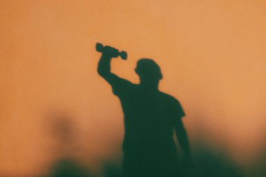 Elinde dambıl olan genç bir adamın gölgesi. Sağlıklı bir yaşam tarzı. Bir erkek figürünün gölgesi..