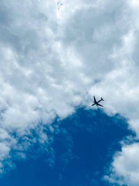 Arka planda gökyüzünde uçan yolcu uçağı. Bulutların üzerinde uçan ticari jet. Uluslararası yolcu taşımacılığı. Dikey fotoğraf.