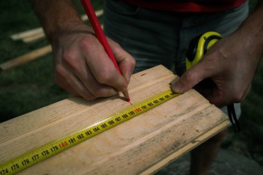 Cropped image of male carpenter marking on plank in workshop clipart