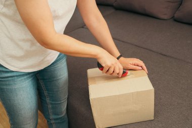 Kadın Kutuyu Açar. Karton kutu teslimatı yapan bir kadın. Karton kutuları bıçakla açan kadın.