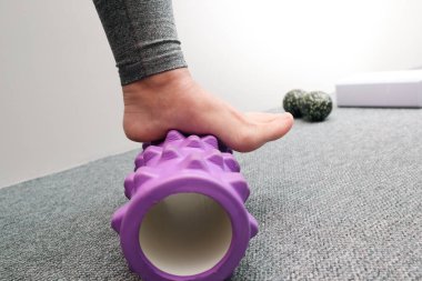Yuvarlanan küçük spor topu olan kadın bacakları. Patenli masaj aleti, kendine masaj ve sağlıklı yaşam tarzı. Ayak kaslarında miyofasyal gevşeme
