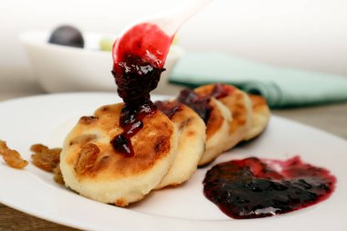 Reçelli kaşık ve peynirli turta hazırlayan kadın eli. Peynirli kekte yaban mersini reçeli. Peynirli kek - üstüne çilek reçeli.