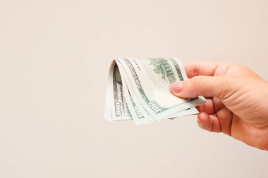 Beyaz arka planda dolarları tutan bir kadın. Bir elde para