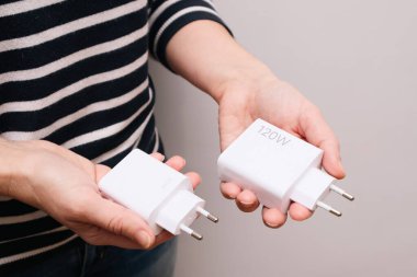 Bir kadının elinde akıllı telefon için hızlı şarj olan güçlü USB cihazları. 120 watt ve 33 watt 'lık şarj aletlerini karşılaştırıyoruz. Akıllı telefon şarj aleti.