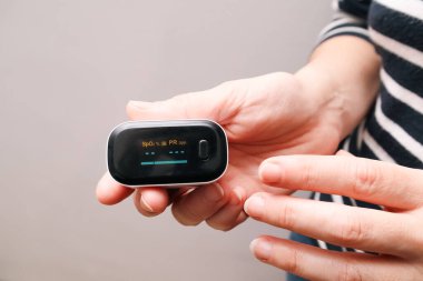 Parmak ucu nabız oksimetresi kullanan bir kadın. Kan Oksijen Seviyeleri ve Nabız İzleniyor