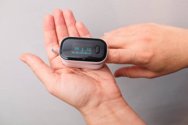 Parmak ucu nabız oksimetresi kullanan bir kadın. Kan Oksijen Seviyeleri ve Nabız İzleniyor