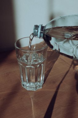 Plastik şişeden bardağa maden suyu döken adam. Erkek eli şişeden bardağa su döker.