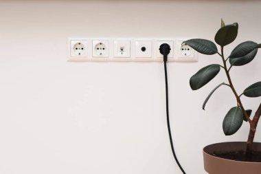 Evin dairesindeki duvarda bir elektrik prizi var. Avrupa 'nın duvar prizine bağlı siyah kablo. Prizle doldur. Bağlantı. Elektrik..