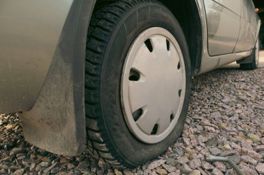 Araba tekerleği düşük hava basıncı. Lastik tamiri. Yolda lastiği patlamış bir araba. Direksiyona odaklan. Yol kenarında zorla durdurulmuş, lastiği patlamış..