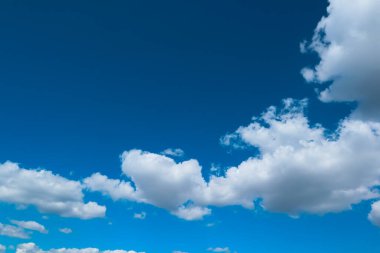 Güneşli bir günde mavi gökyüzü ve bulutlar. Mavi gökyüzü ve beyaz bulutlar. Mavi gökyüzü arka planda bulutlar, bulutlu ve gökyüzünde güneşli güzel bir manzara..