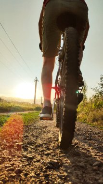 Gün batımında çakıl yolda bisiklete binen bir adam. Gün batımında Bisikletçiler Yukarı Gidiyor