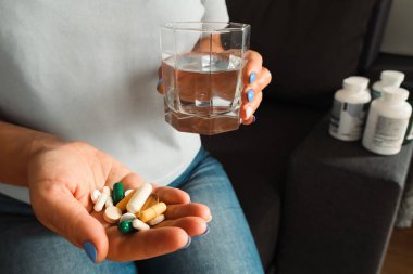 Evde tedavi için vitamin ya da hap alan bir kadın. Kadın vitamin ve takviye alıyor. Tıbbi konsept.