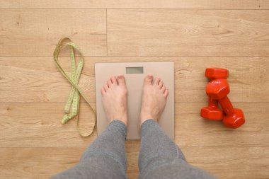 Ağırlığı kontrol eden bir kadın. Evde tartılan bir kadın. Tartı tartısında duran genç bir kadının yakın çekim görüntüsü.