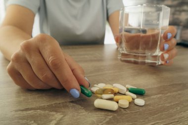 Hapları şişeden döken kadın eli. Elinde ilaç tutan bir kadın.