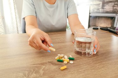 Hapları şişeden döken kadın eli. Elinde ilaç tutan bir kadın.