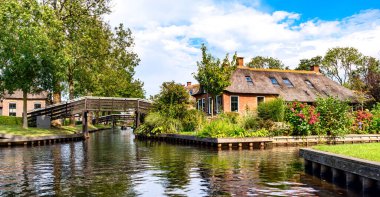 Saz çatılı kulübeleri ve tekneleri olan sakin bir nehir kenarı köyü.