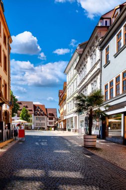 Gotha, Thüringen 'deki kaldırımlı yaya caddesi, parlak bir yaz gününde renkli cephelerle ve butik mağazalarıyla dolu.