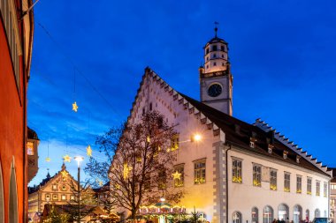 Ravensburg 'da romantik bir Noel pazarı. Tarihi belediye binası mavi bir gökyüzünün altında aydınlanıyor.