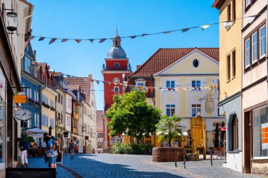 Almanya 'nın Gotha kentindeki Old Town Hall yakınlarındaki şenlikli caddede renkli bayraklar, tarihi binalar ve kaldırım taşı bir sokak var.