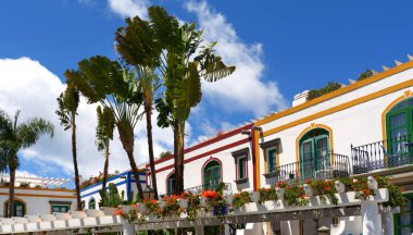 Çiçekli balkonlar, palmiye ağaçları ve Puerto de Mogan, Gran Canaria 'da mavi gökyüzünün altında renkli yüzler.