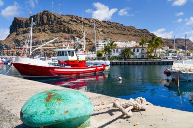 Puerto Mogan 'ın balıkçı teknesi ve dağı güneşli bir yaz günü İspanya' nın Gran Canaria kentinde.
