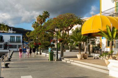 Puerto de Mogan, Gran Canaria 'da altın akşam ışığında renkli liman evleri ve palmiye ağaçları gün batımında