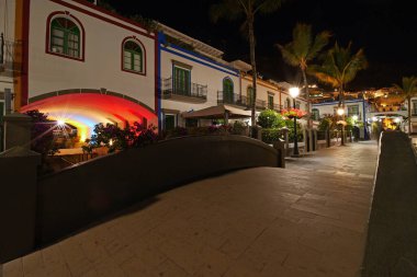 Puerto de Mogan, Gran Canaria 'da altın akşam ışığında renkli liman evleri ve palmiye ağaçları gün batımında