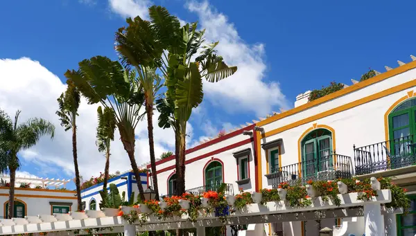 Çiçekli balkonlar, palmiye ağaçları ve Puerto de Mogan, Gran Canaria 'da mavi gökyüzünün altında renkli yüzler.
