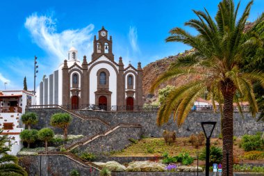 Santa Lucia Kilisesi, Gran Kanarya 'daki kayalık manzaradan önce palmiye ağaçları ve teraslı bahçe.