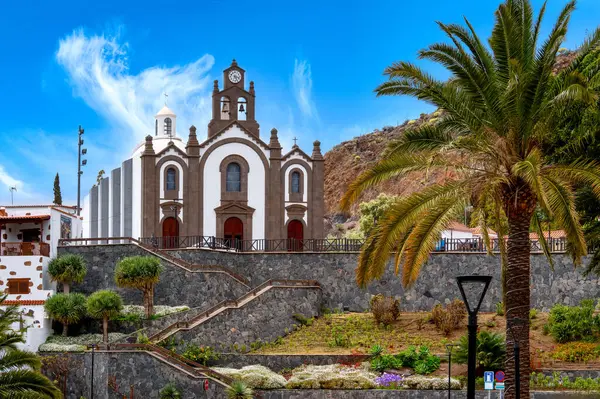 Santa Lucia Kilisesi, Gran Kanarya 'daki kayalık manzaradan önce palmiye ağaçları ve teraslı bahçe.