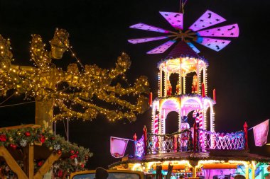 Yılbaşı pazarında renkli aydınlatılmış Noel piramidi. Noel kültürünün sembolü: biblolar, ışıklar ve festival tasarımlı piramit