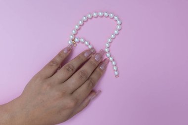 Şık kadın manikürü, pembe arka planda güzel kadın elleri.