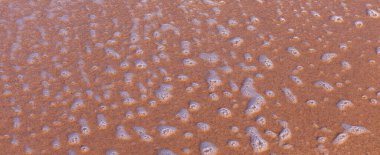 Deniz suyu, Akdeniz 'in beyaz deniz köpüğü güneşli bir yaz gününde yukarıdan kumlu sahilin yakın görüntüsü çekildi.