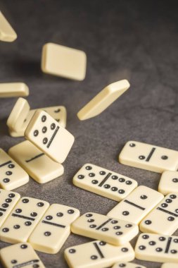 Klasik dominoların birkaç taşı karanlık bir arka planda masanın üzerinde yatıyor.
