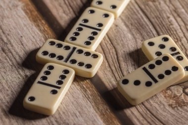 Klasik dominoların bir kaç taşı ahşap bir masanın üzerinde duruyor, yakın plan, yan görünüşte çekilmiş.