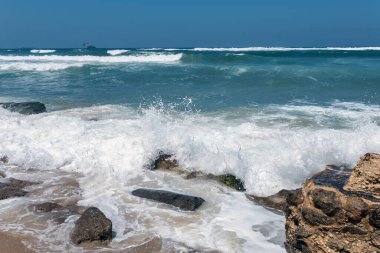 Deniz dalgaları kayalıklarda kırılır. Sıcak bir yaz gününde, alışılmadık şekillerde güzel sıçramalar oluşturur.