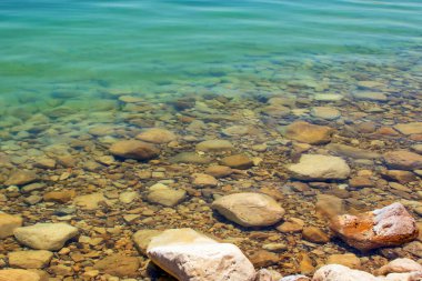 Ölü denizin sıcak ve sakin sularında büyük taşlar.