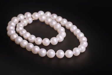 Siyah bir arka planda beyaz deniz incilerinden yapılmış lüks kadın kolyesi, güzellik ve moda kavramı.