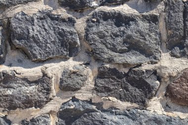 Duvarın dokusu gri, pürüzlü taş kullanılarak oluşturulur.