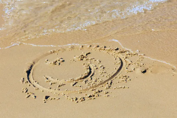 Kumsalda gülümseyen boyalı bir yüz.