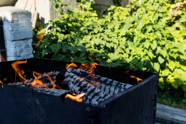 Kömürün üzerinde et pişirmek için ızgarada odun yakıyorum.