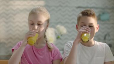 Kız ve oğlan kahvaltıda taze portakal suyu içiyor. Yüksek kalite 4k görüntü